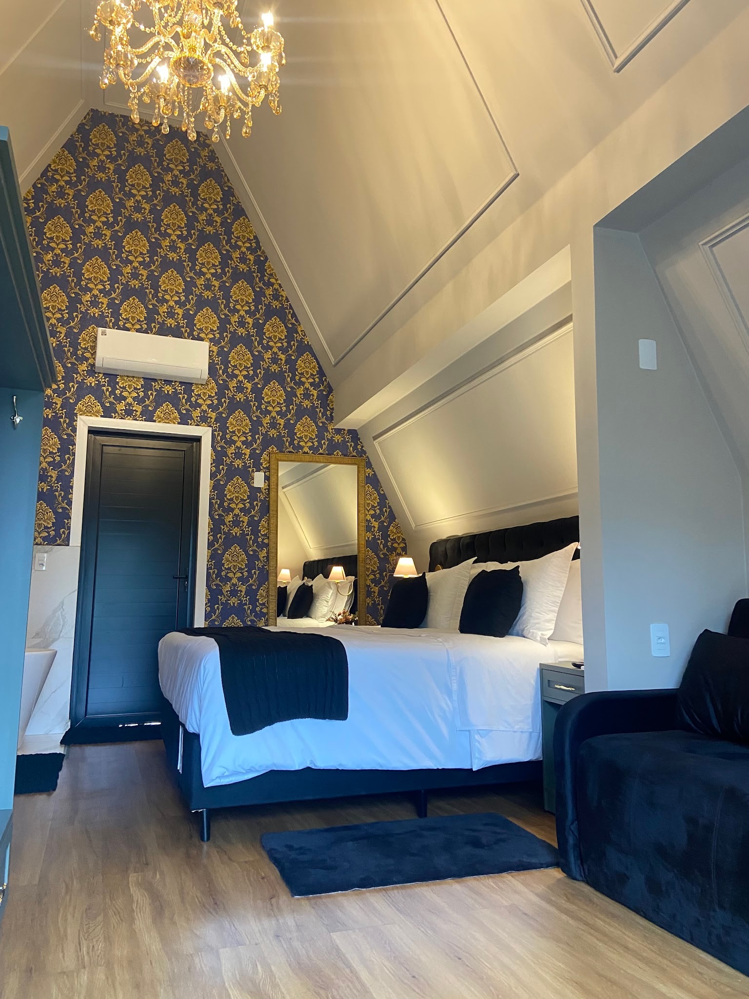 Chalé com cama king, sofá de veludo azul e papel de parede azul e dourado