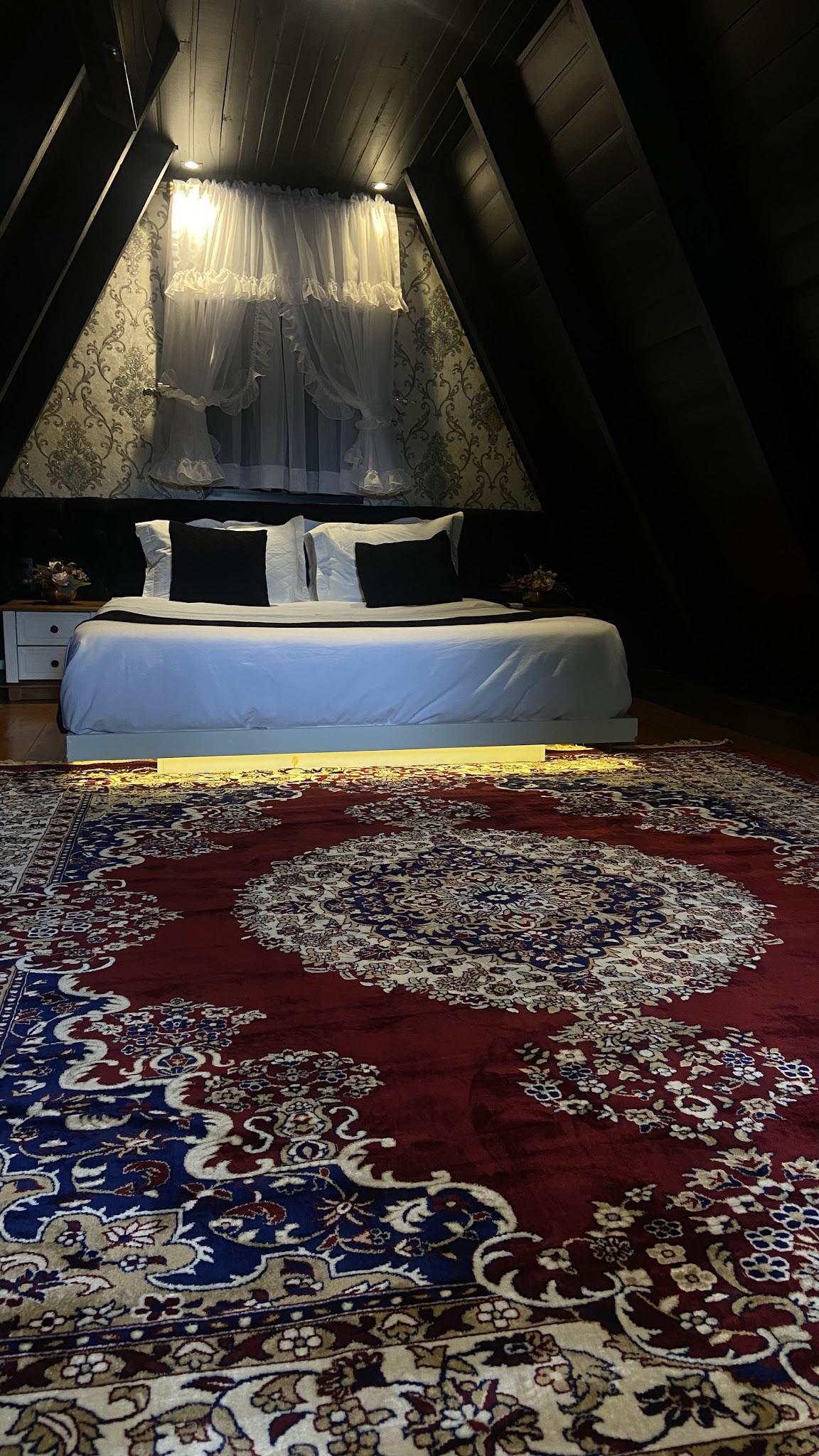 Cama king size no piso superior do Chalé Duplex, sobre tapete persa e forro preto