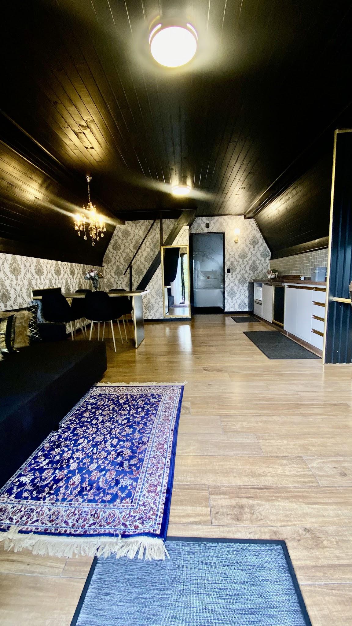 Piso inferior do Chalé Duplex com sala de estar, cozinha ao fundo e tapetes azuis