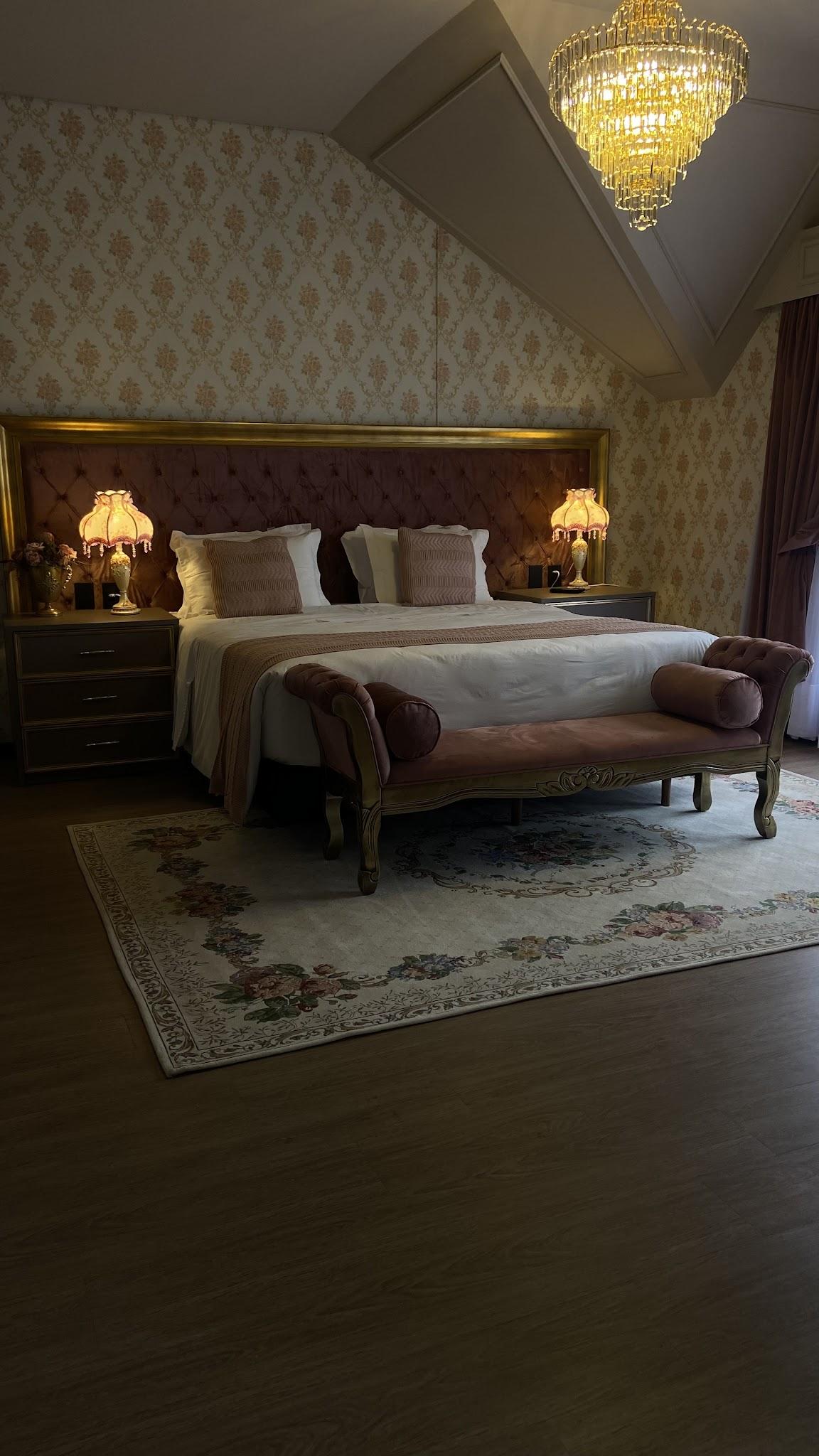 Cama king size da Suíte Imperial com recamier aos pés e papel de parede damasco dourado
