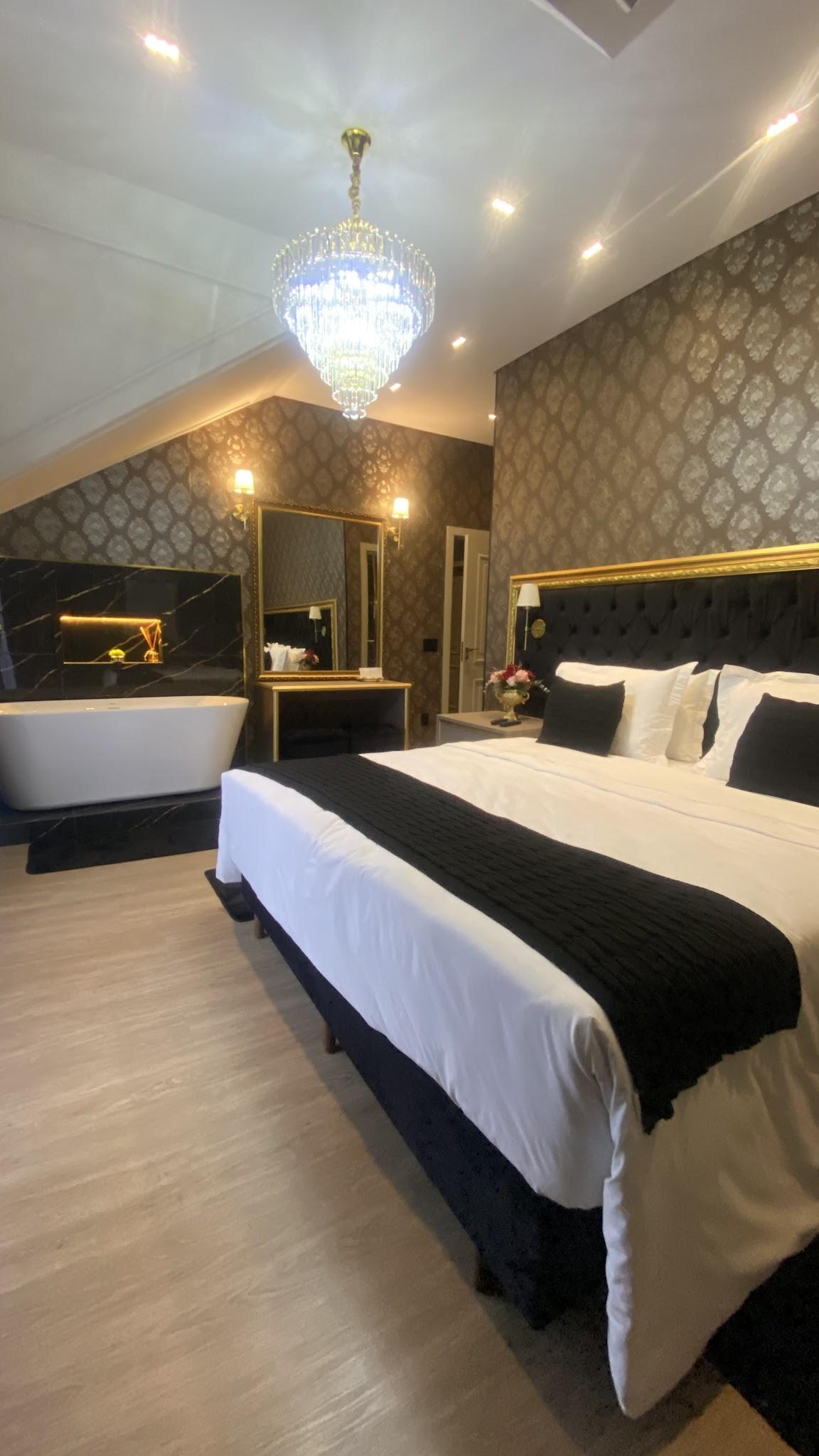 Cama king size da Suíte Majestic com enxoval preto e branco e banheira de imersão ao fundo
