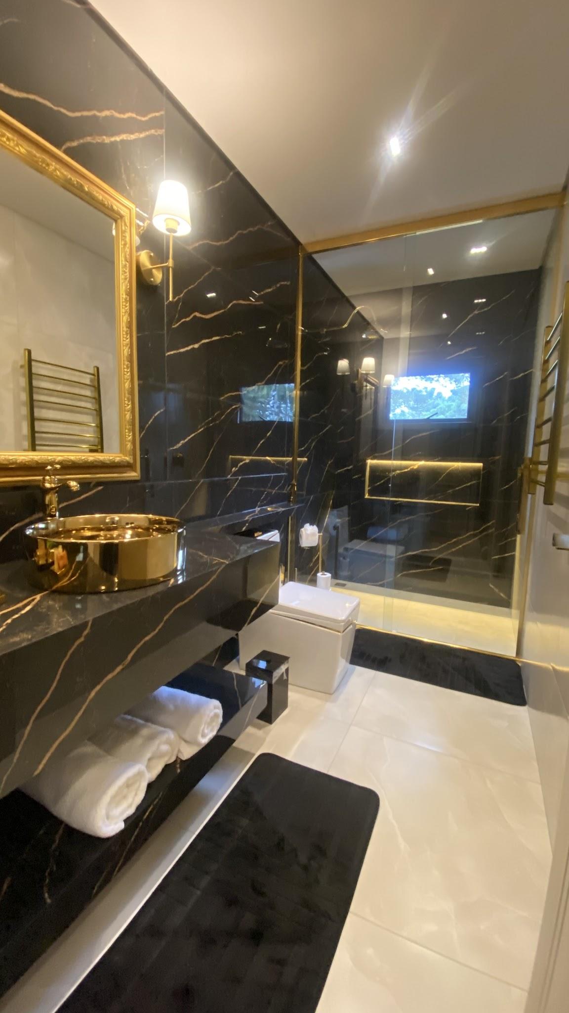 Banheiro da Suíte Majestic em mármore preto com cuba dourada e box de vidro